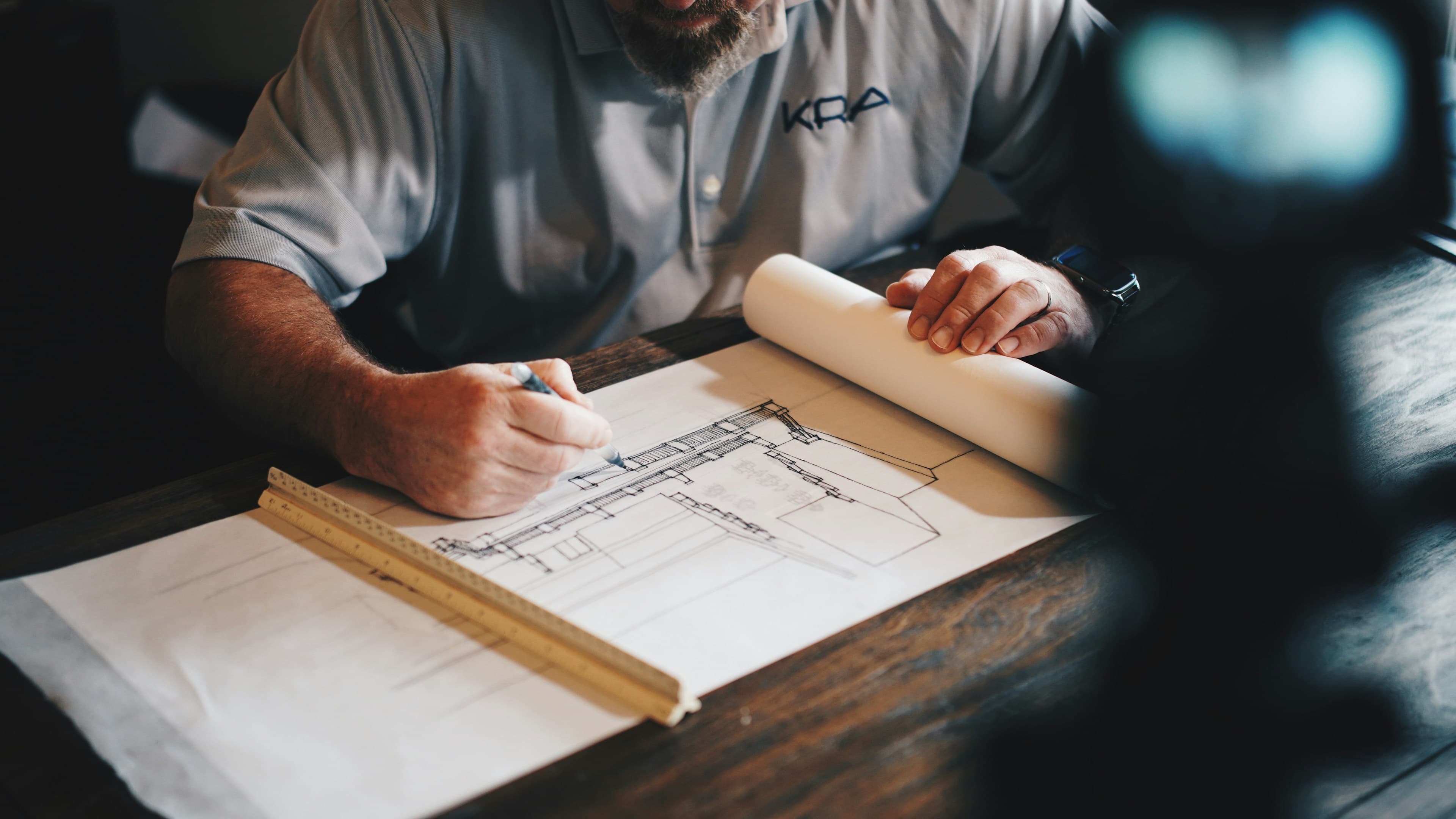 Architect marking a building-section drawing with a pencil and a wooden scale ruler