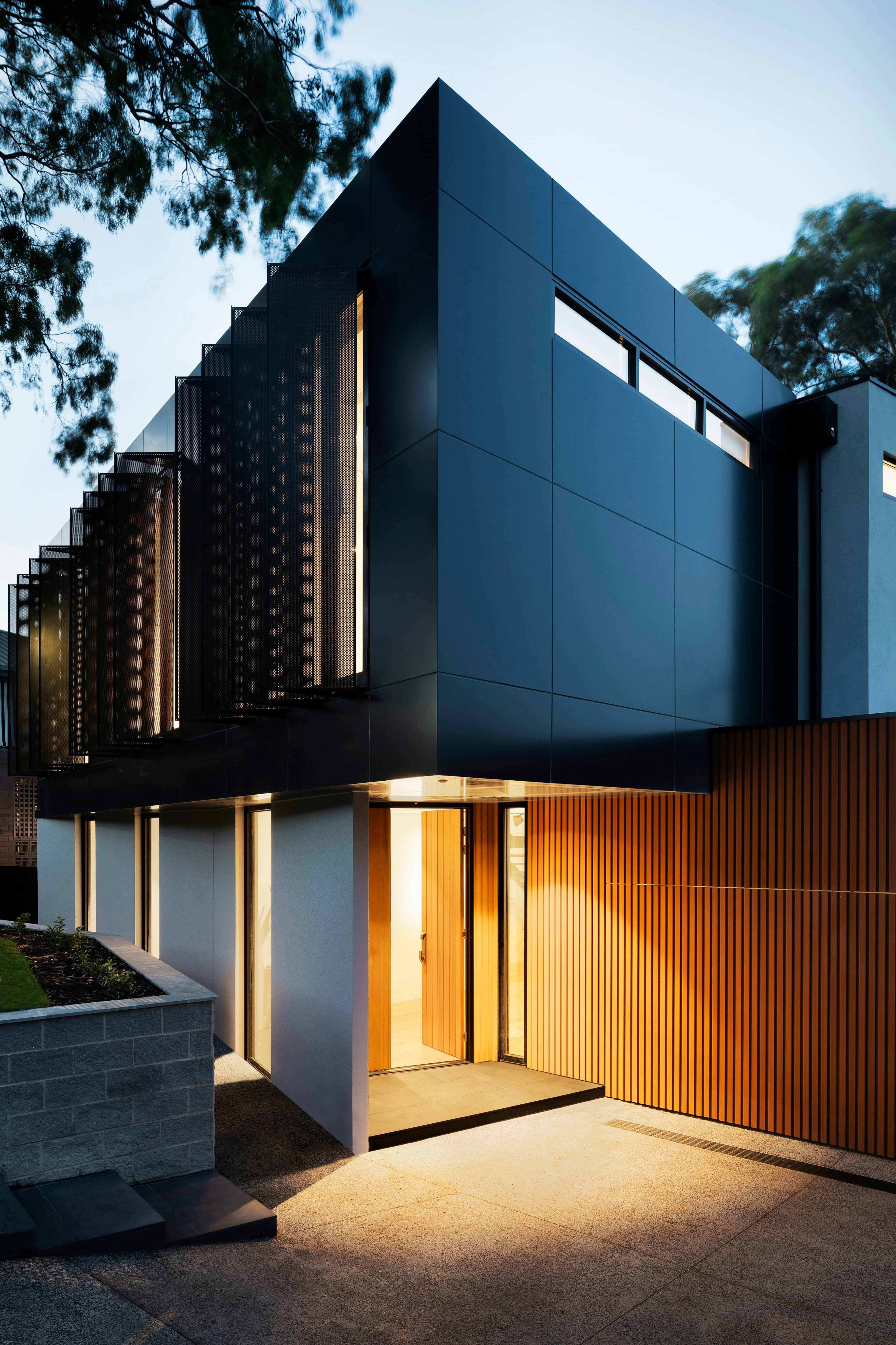 Modern two-storey white house with dark window frames, timber soffits, and a swimming pool in the foreground