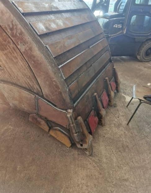 Large fabricated steel bucket attachment inside a workshop