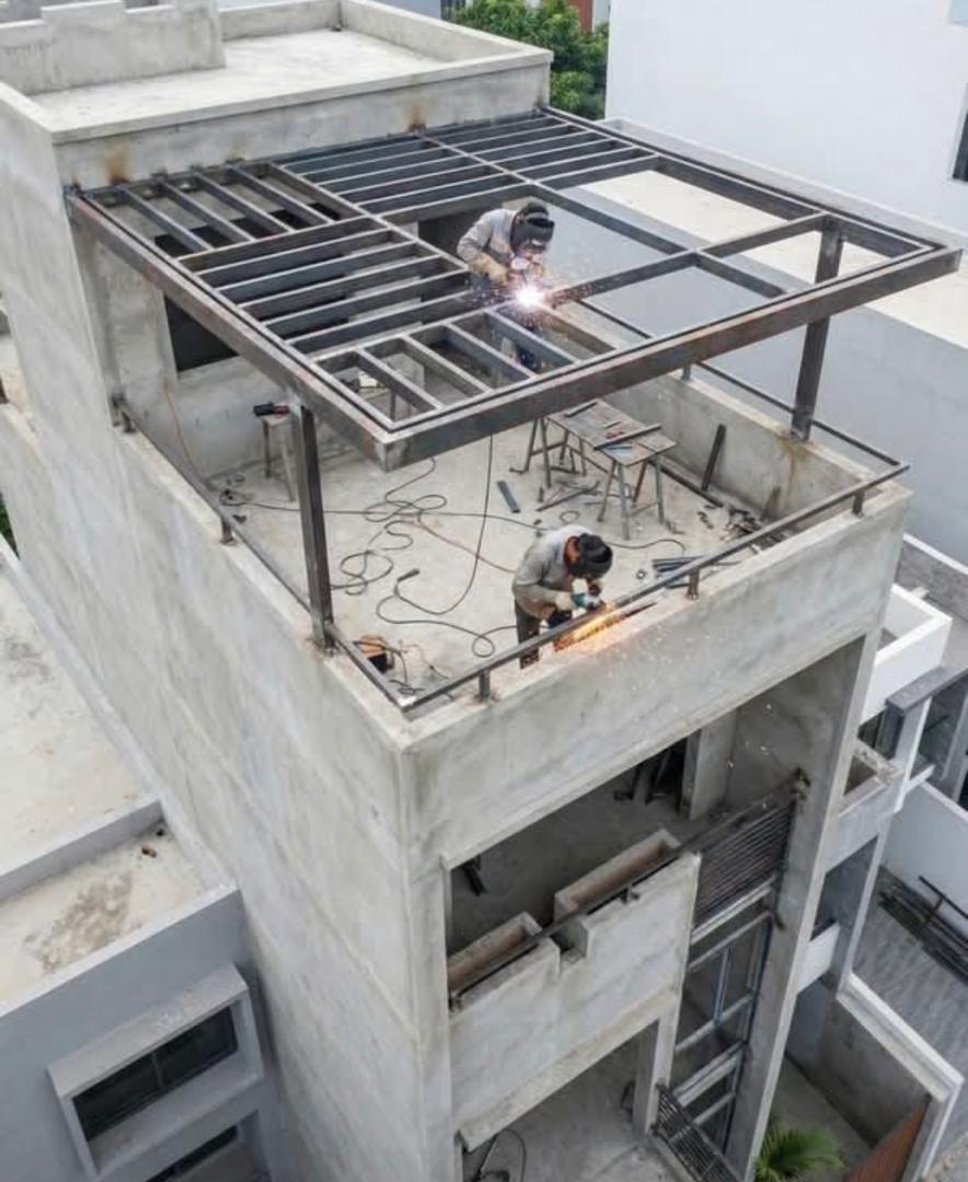 Two welders assembling a rooftop steel frame