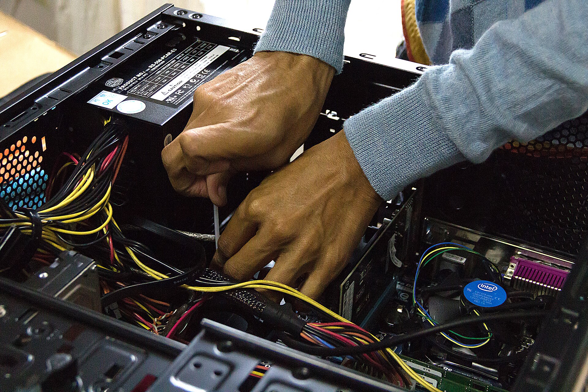 Technician's hands replacing a component inside an open desktop computer case